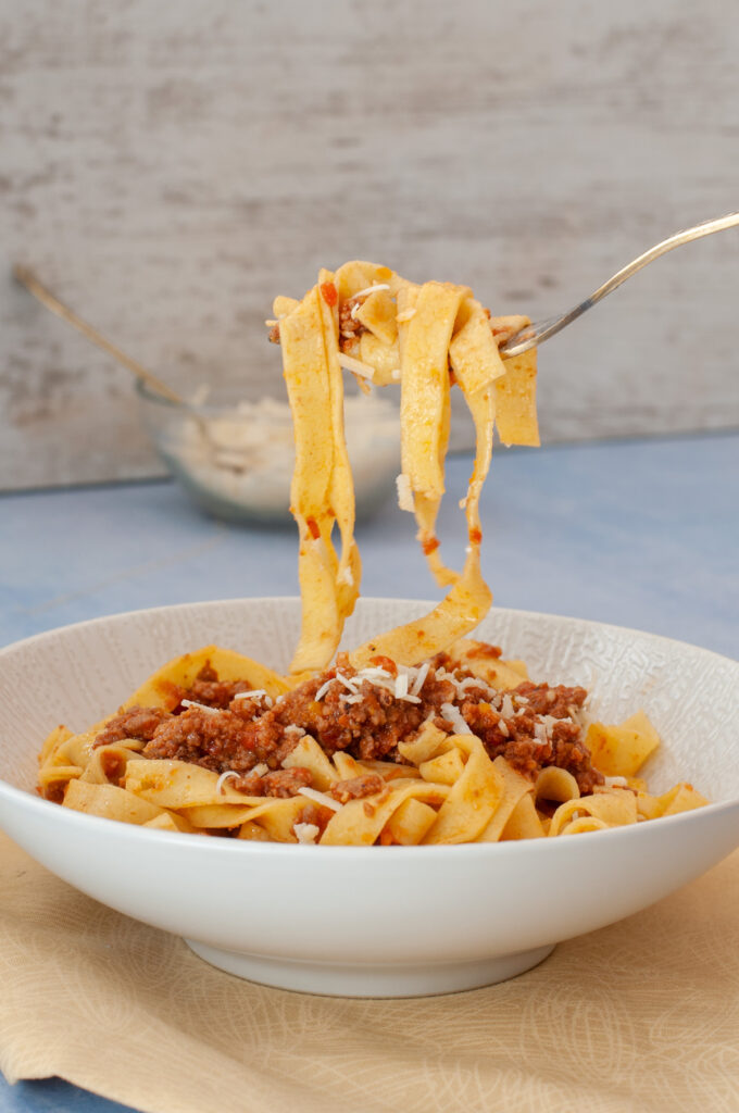 bolognese dans une assiette blanche soulevée par une fourchette