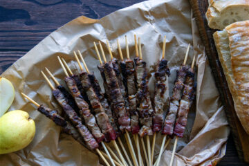 arrosticini cuites avec ciabatta à côté sur fond de bois