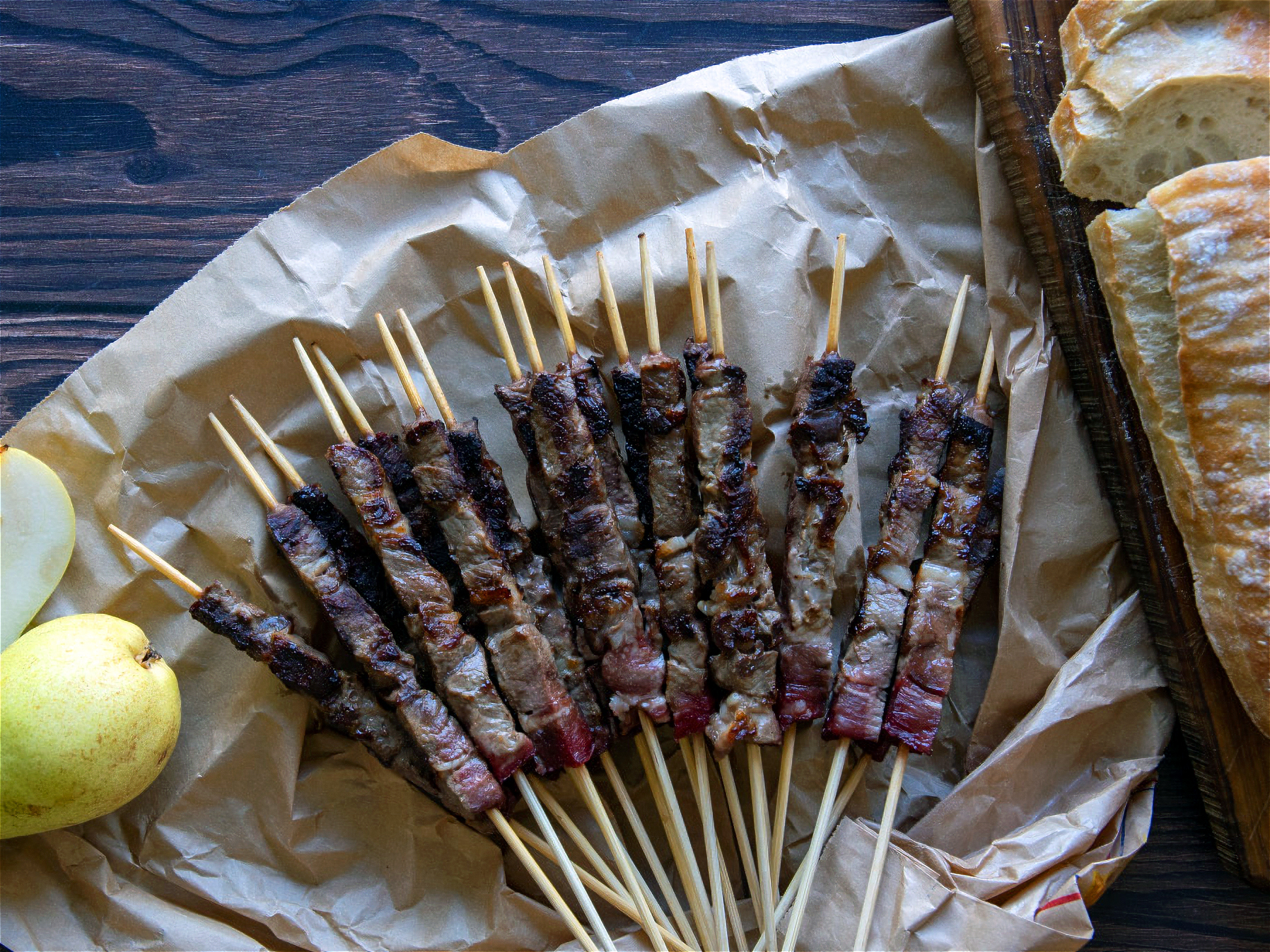 arrosticini cuites avec ciabatta à côté sur fond de bois