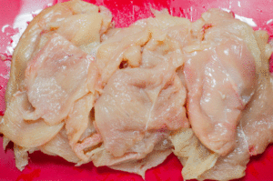 Escalopes de poulet panées croustillantes au four (sans œuf) - Coupez les poitrines de poulet en tranches et assaisonnez avec du sel, du poivre et de l'huile d'olive. Mélangez bien pour que l'huile aide la chapelure à adhérer au poulet