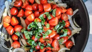 Pâtes italiennes aux crevettes et tomates cerises - Lorsque l'échalote devient translucide, ajoutez les tomates cerises, coupées en deux, et les feuilles de basilic, ciselées. Mélangez et assaisonnez
