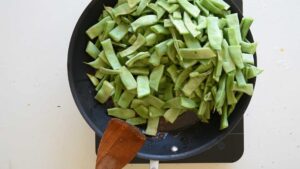 Recette Facile et Authentique de Haricots Verts à l’Italienne avec Tomates - Ajoutez les haricots verts dans la poêle et faites-les sauter jusqu'à ce qu'ils prennent une couleur verte vive et commencent à caraméliser