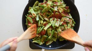 Recette Facile et Authentique de Haricots Verts à l’Italienne avec Tomates - Salez et mélangez jusqu'à ce que les haricots verts et la sauce tomate soient bien enrobés