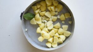 Recette facile de pommes de terre rôties croustillantes à l’italienne - Ajoutez les gousses d’ail, pelées et coupées, la branche de romarin et la feuille de laurier dans le plat.