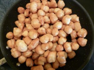 Recette traditionnelle de Struffoli au Cognac - Versez les struffoli dans une grande poêle et ajoutez le miel. Mélangez bien à feu moyen jusqu'à ce que le miel caramélise et enrobe complètement les struffoli